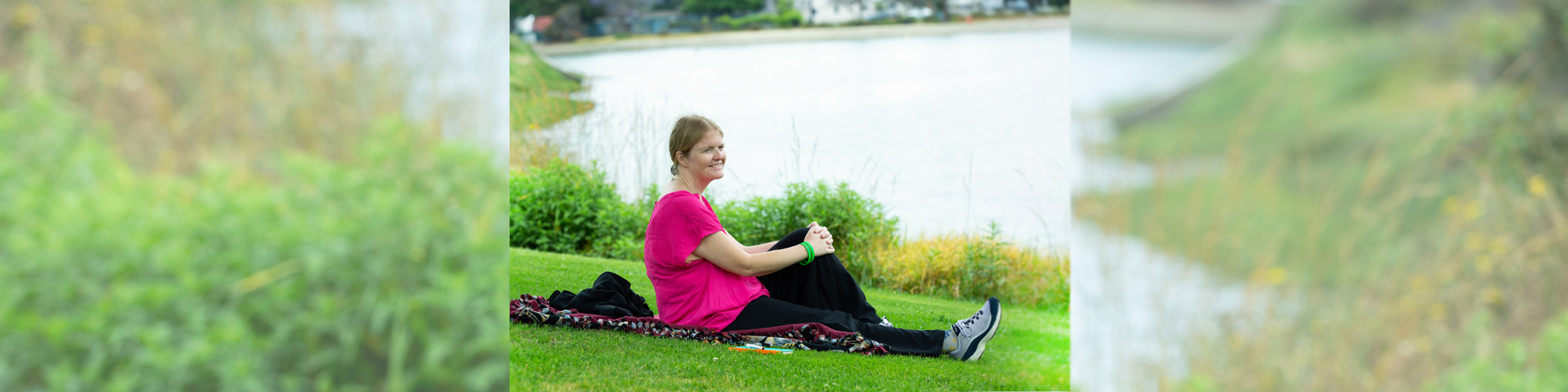 woman sitting on grass near lake