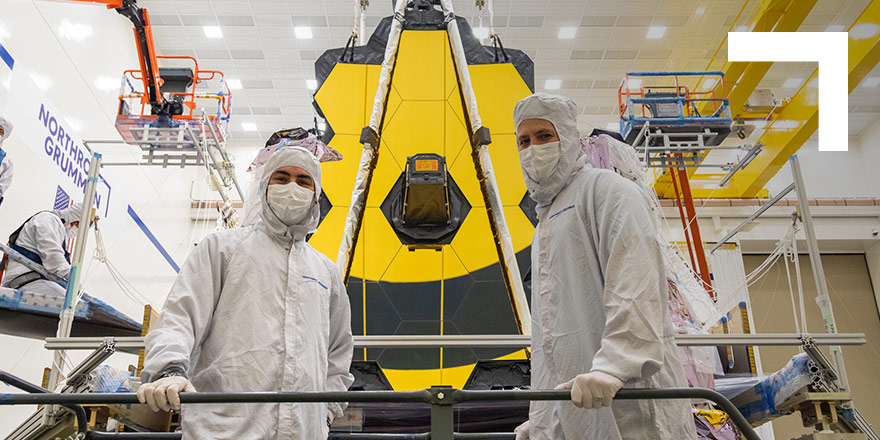 two engineer standing in front of the Webb telescope
