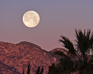 This full moon is about to set over the Huachuca Mountains to the west of Sierra Vista, Arizona just as the sun is rising over the Dragoon mountains to the east.