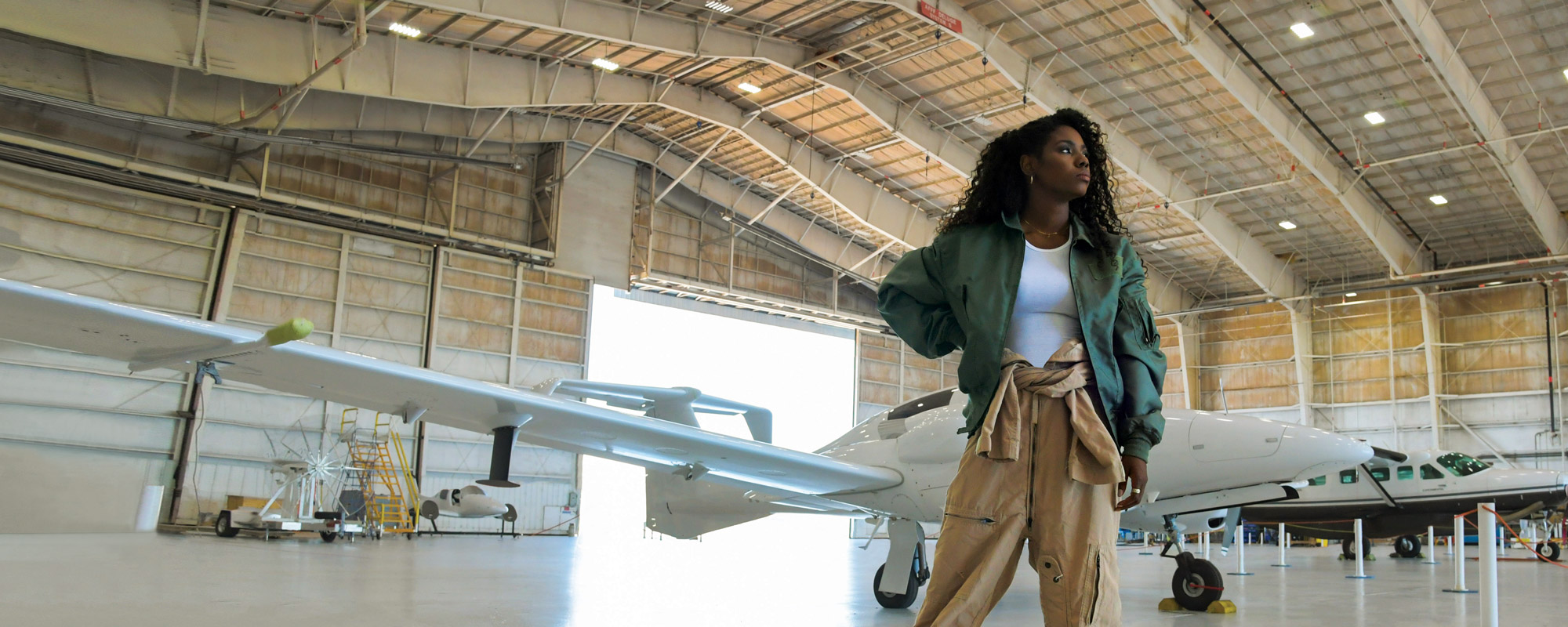 African American Female standing in Hangar with Large plane