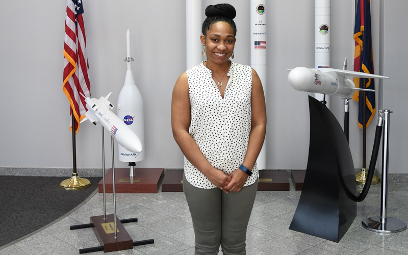 African American Female standing in front of model rockets