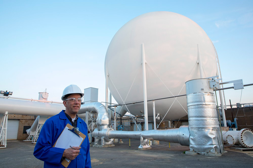 Man in hard hat in front of Northrop Grumman Vacuum Sphere Ejector System