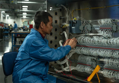 Technician works with many wires in an manufacturing setting.