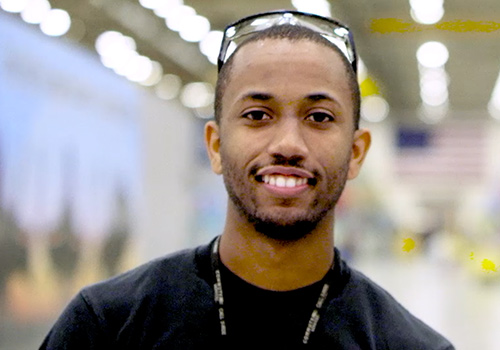 Black man smiles posing in hangar