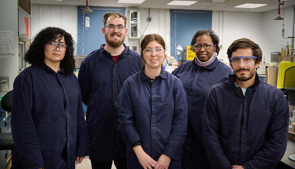 five employees wearing blue coveralls