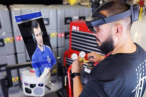 a man wears a XR headset to watch a video to work on machinery (image sized for a feature tile)